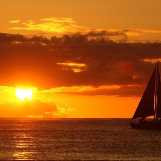 Landscape view of a boat sailing at sunset near Waikiki Resort Hotel by Sono