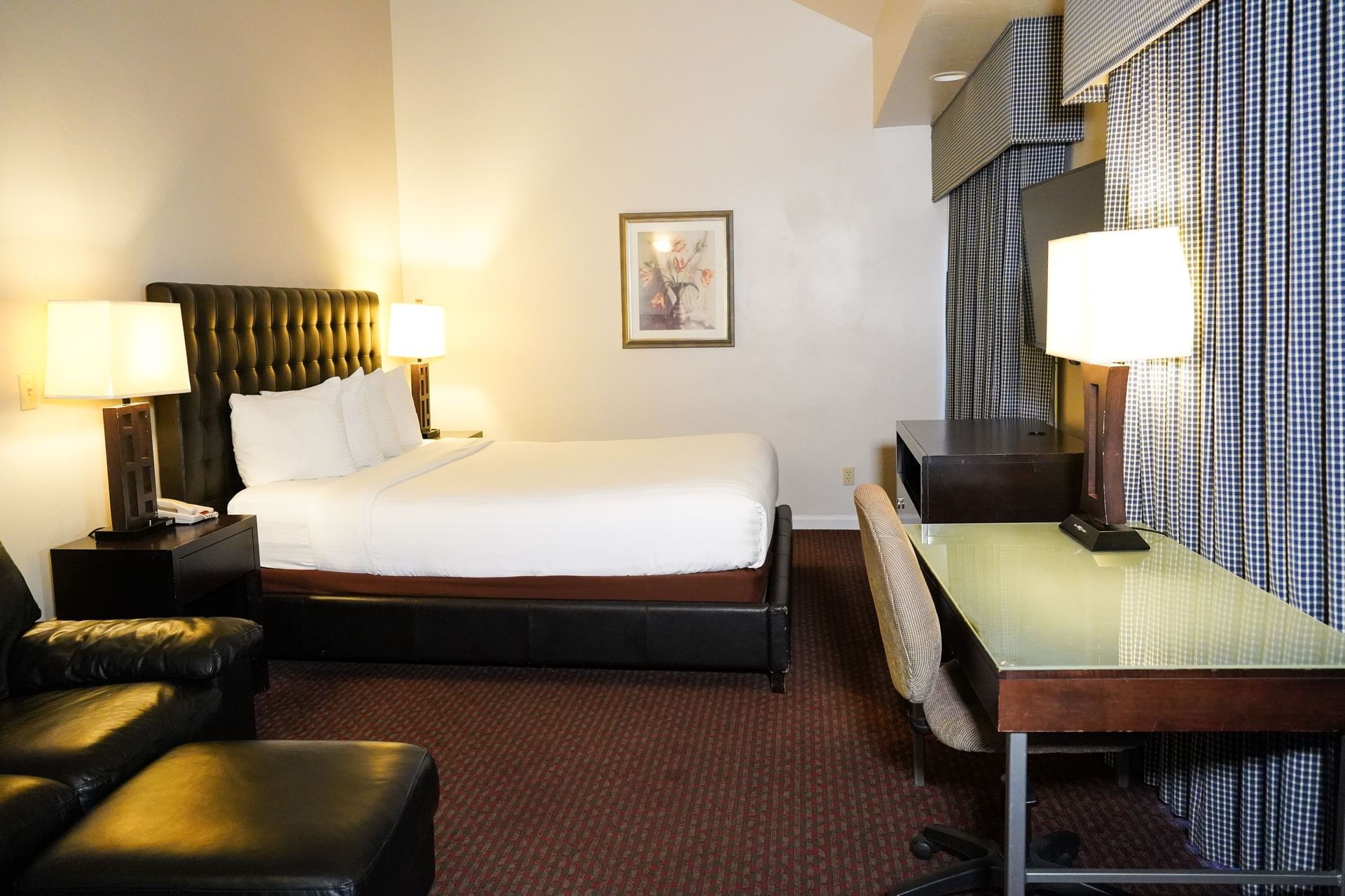 A hotel room with a bed, desk, chair, and TV