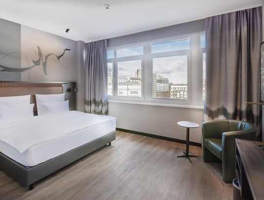 A large bed with a window overlooking the city view in the Classic Triple Room at Titanic Comfort Kurfürstendamm