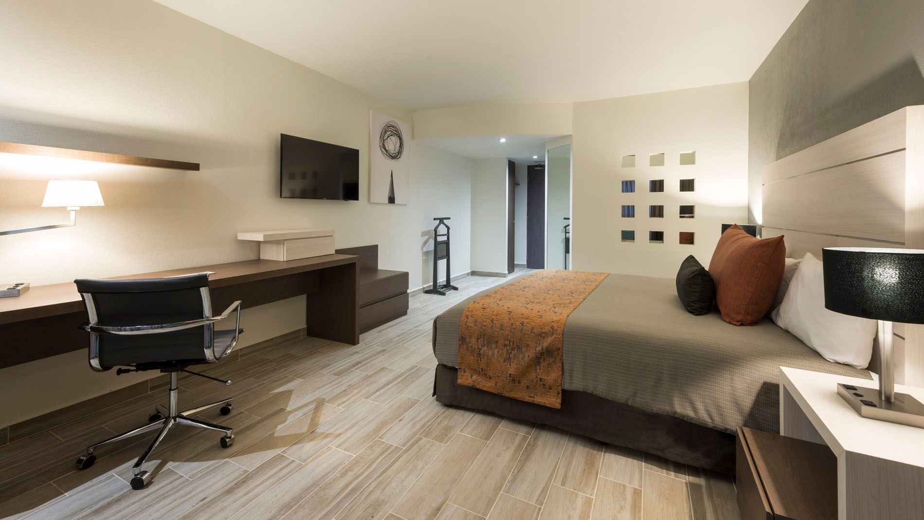 Workspace and TV facing the cozy bed in the King Deluxe Room with wooden floors at Real Inn San Luis Potosi