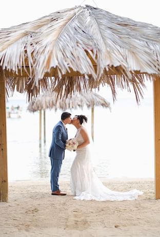 Newlyweds kissing in a Copa Beach at Copamarina Weddings