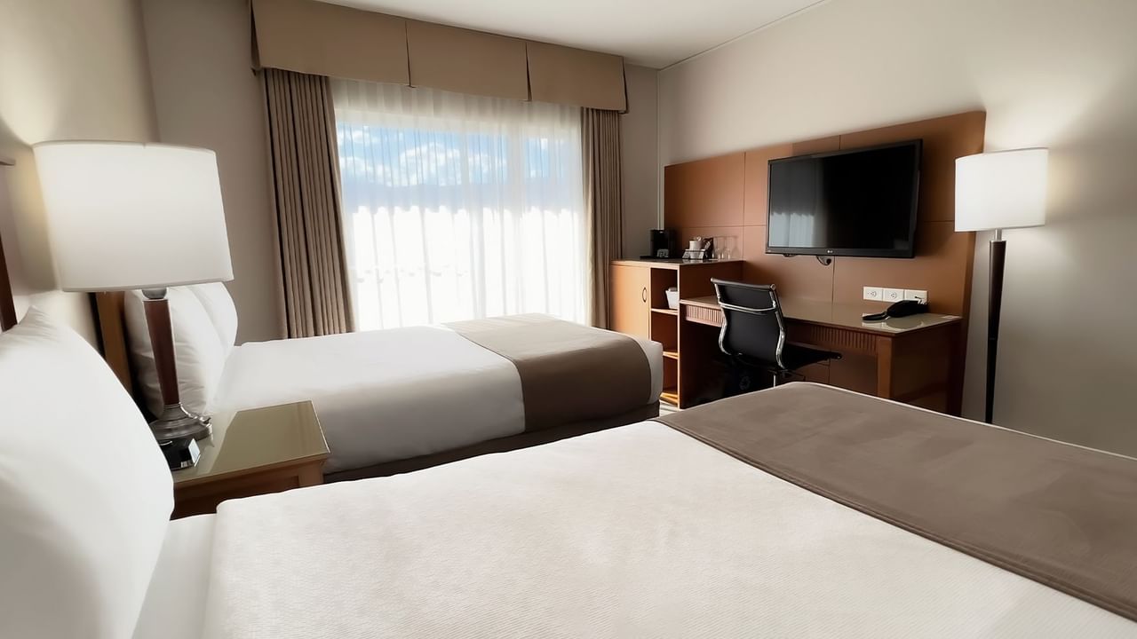 Guest room with two double beds, large desk, tv, window, chair