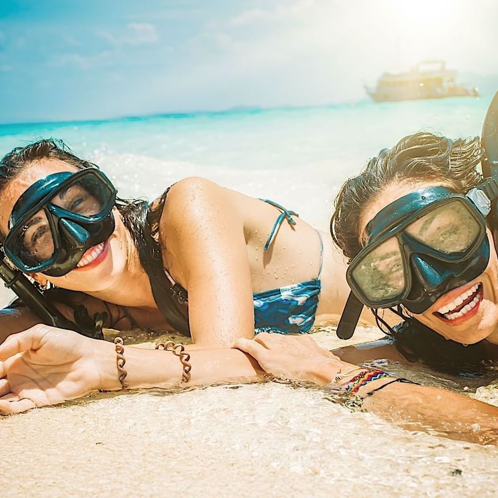 Two female divers laying on the beach