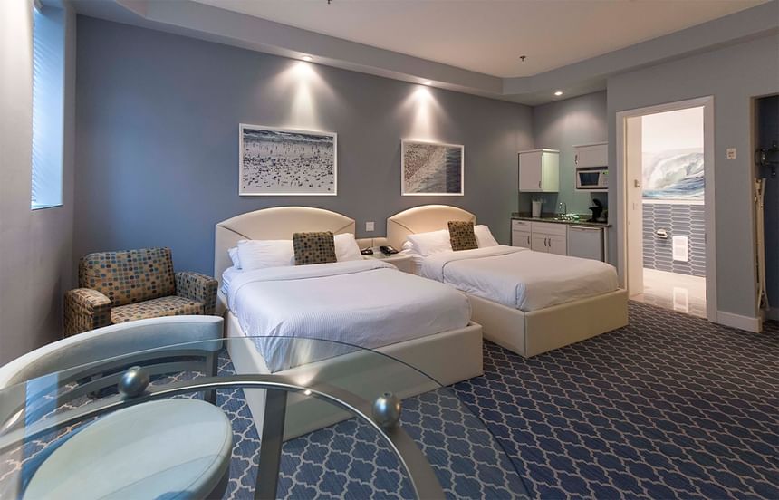 two queen beds sit side by side with blue walls and blue carpet 