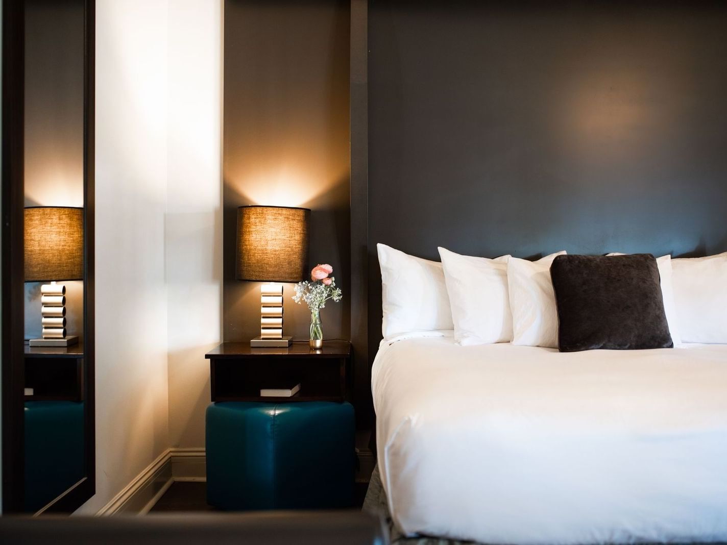 Modern bedroom at The White House Hotel with a white bed, dark wall, and a glowing bedside lamp
