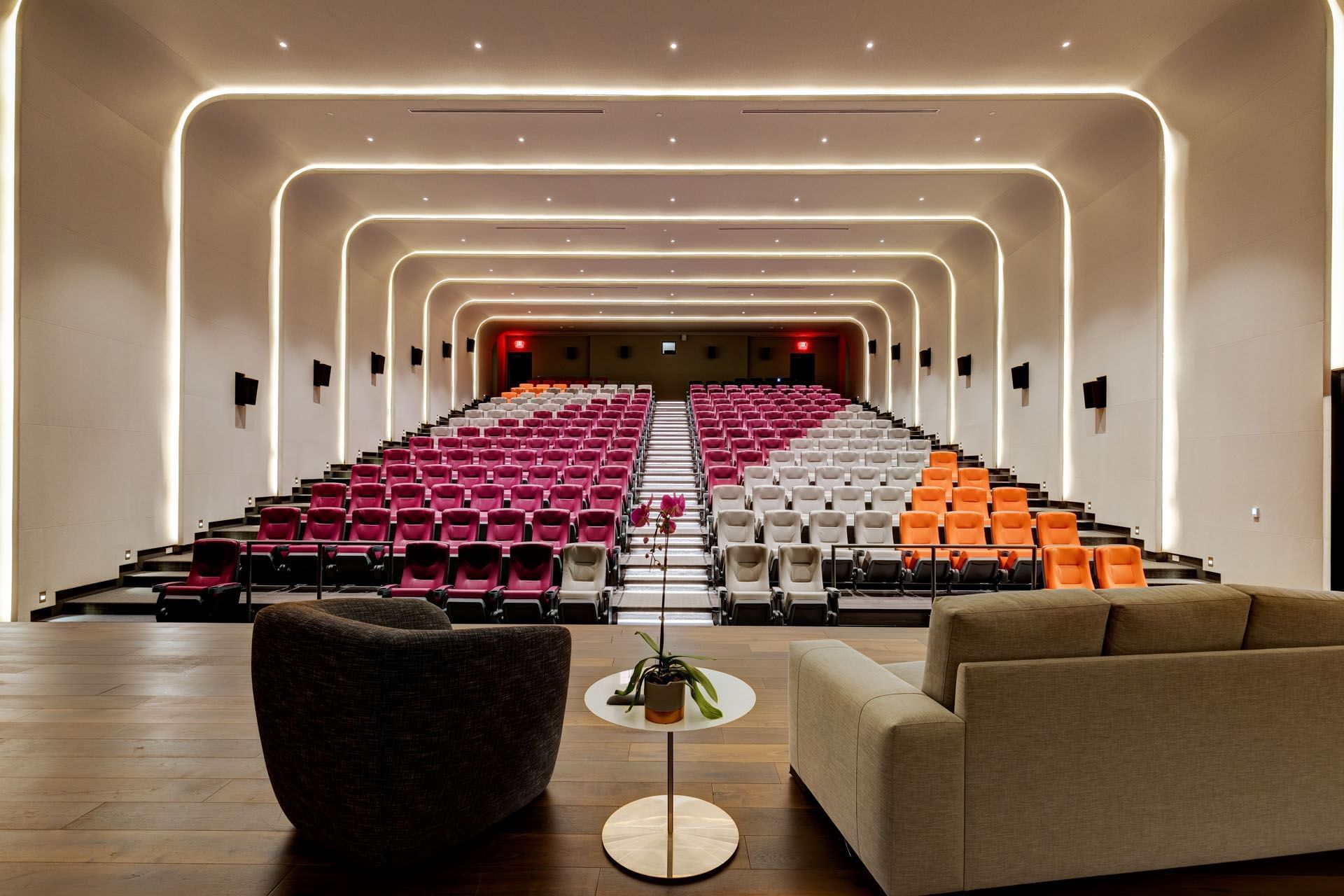 Modern auditorium with colorful tiered seating and warm LED lighting strips along the walls at Hotel X Toronto
