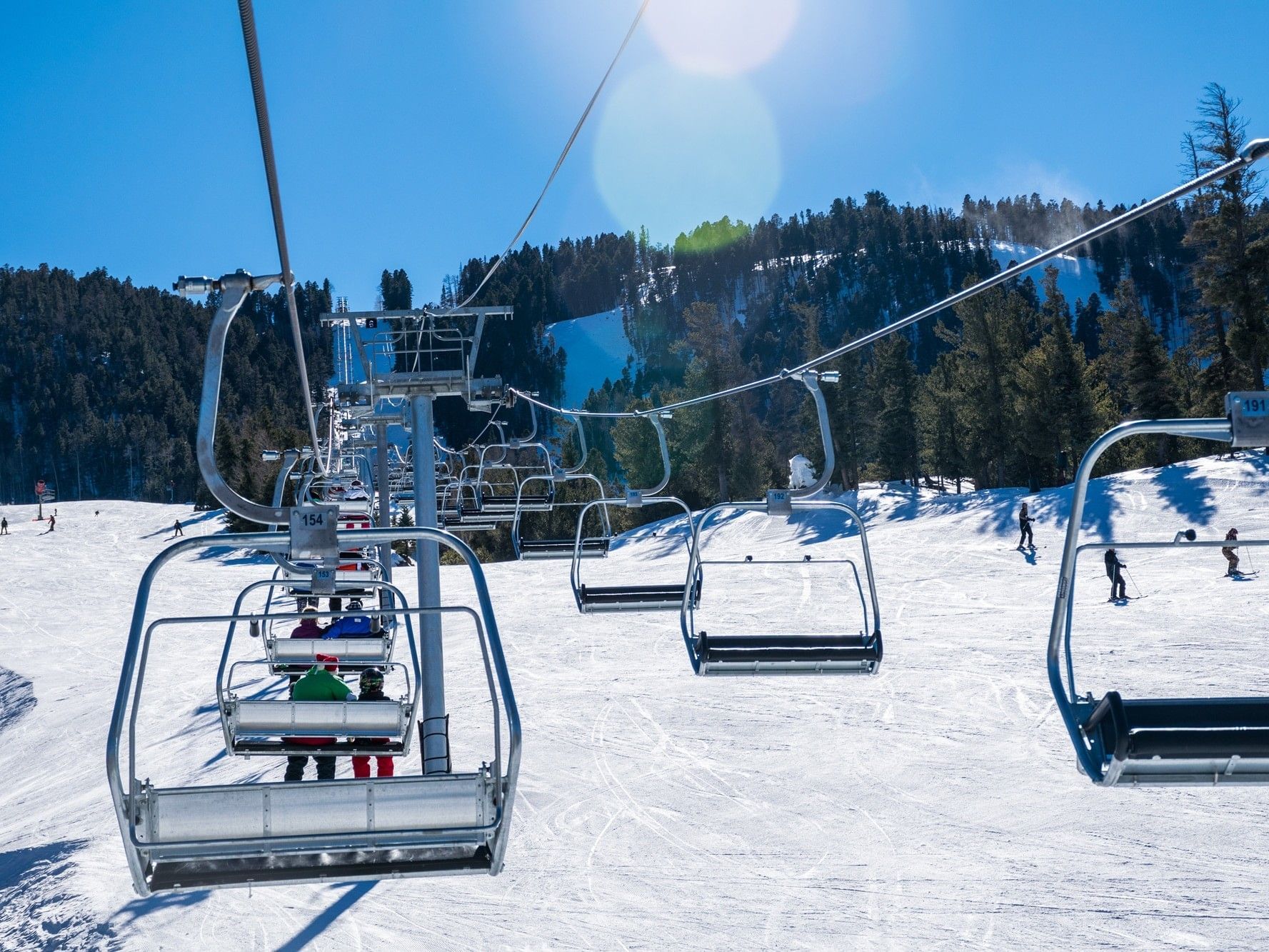 ski lift, people riding and people skiing underneath lift