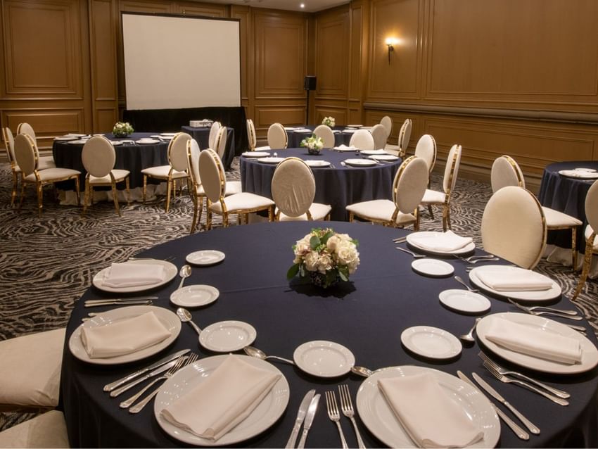 Salon Virreinal with navy blue tablecloths and a large projector screen at Quinta Real Monterrey