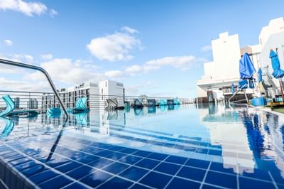 Rooftop Pool with sun loungers and sun huts on a sunny day at Fairwind Hotel Miami