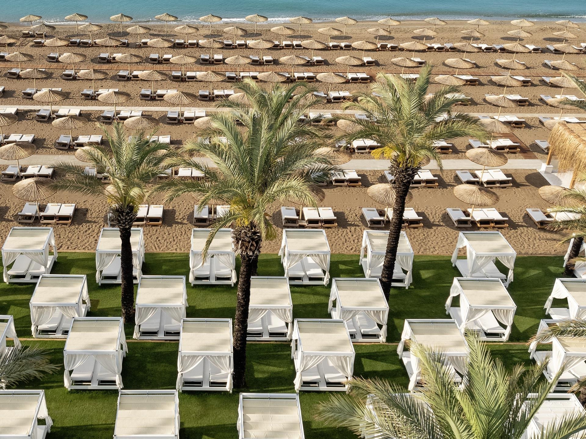 Aerial view of sun loungers under Pier cabanas overlooking the ocean near Titanic Deluxe Lara