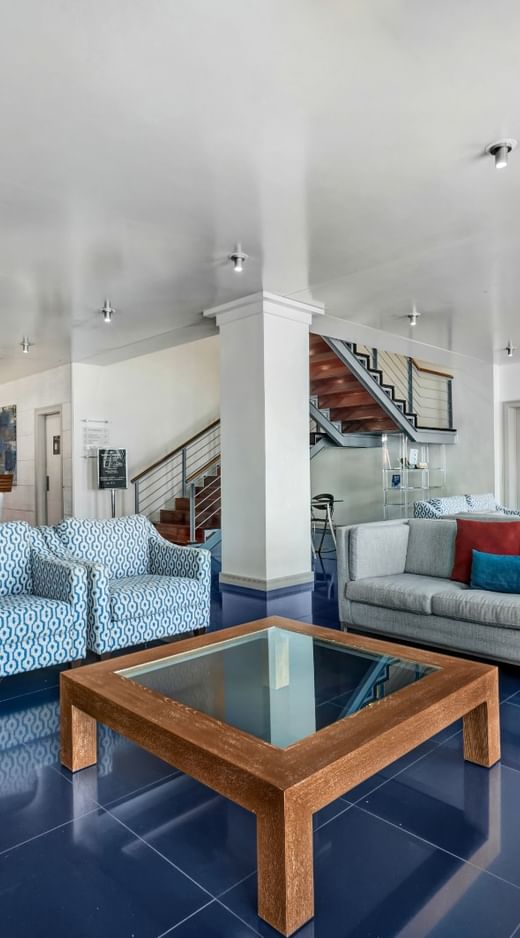 A modern lounge at Hotel Do Caracol with plush sofas and armchairs on a glossy blue tiled floor