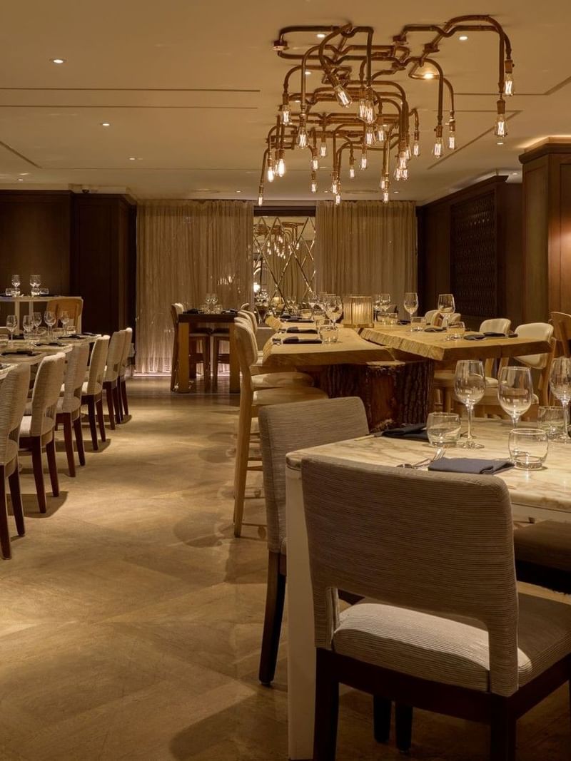 Elegantly decorated May Fair Kitchen restaurant with long dining tables and chairs at The May Fair Hotel, London.
