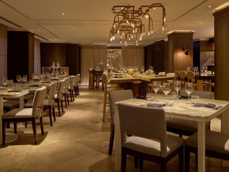 Elegantly decorated May Fair Kitchen restaurant with long dining tables and chairs at The May Fair Hotel, London.
