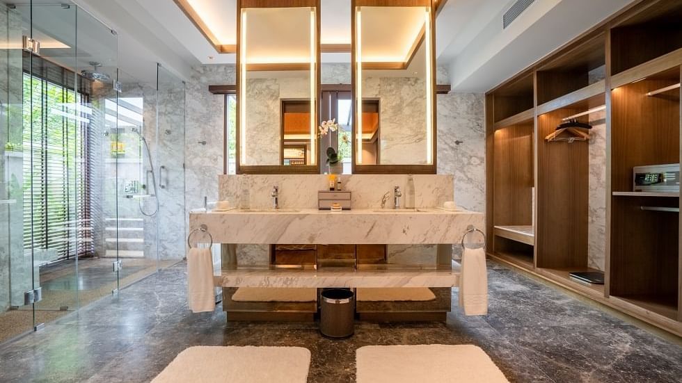 Luxurious Royal Villa bathroom with marble vanity, dual mirrors, glass shower, and wooden accents at The Banjaran Hotsprings Retreat.