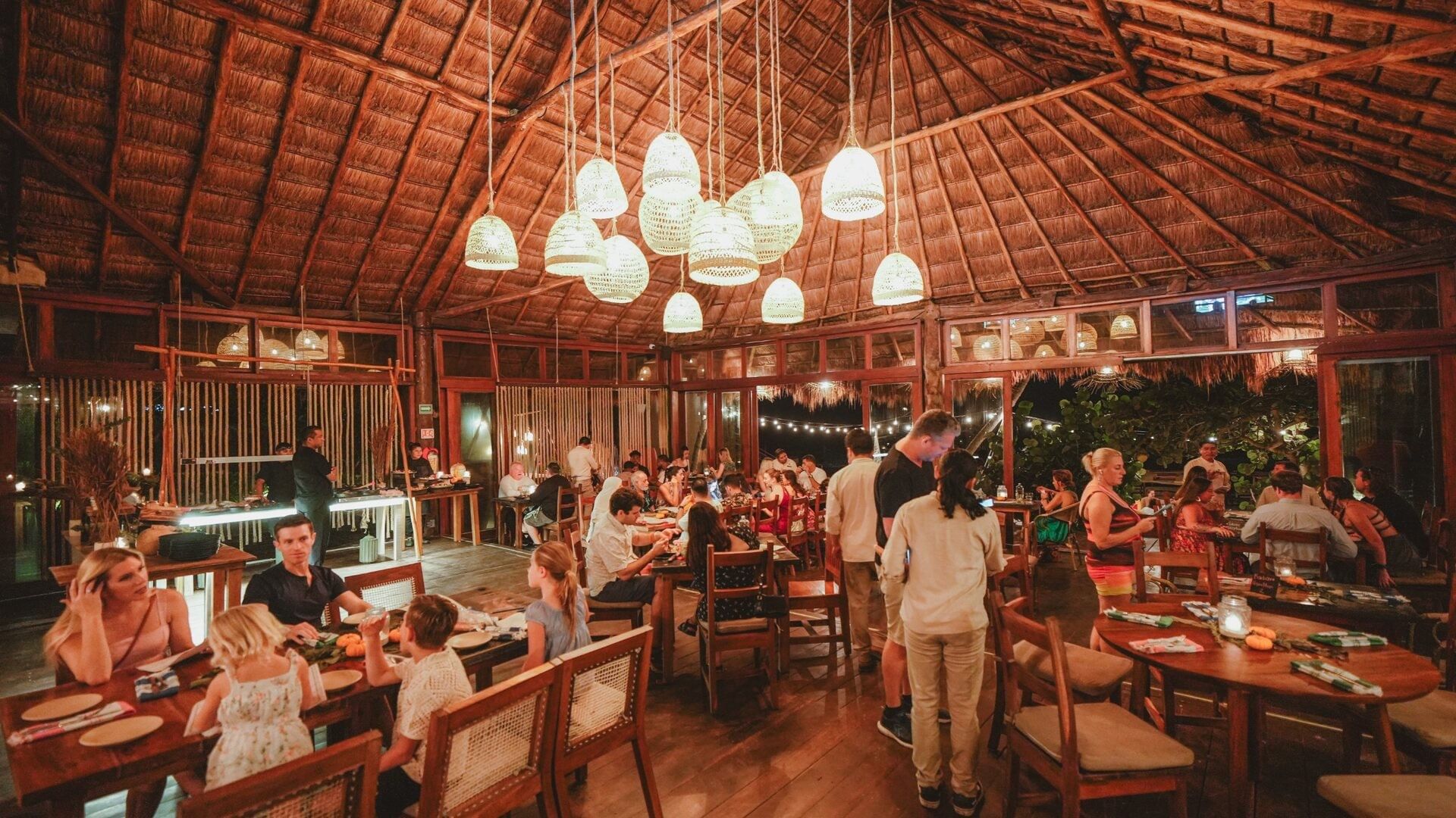 Families gathering for dinner beneath the woven lamps of La Zebra’s palapa restaurant.