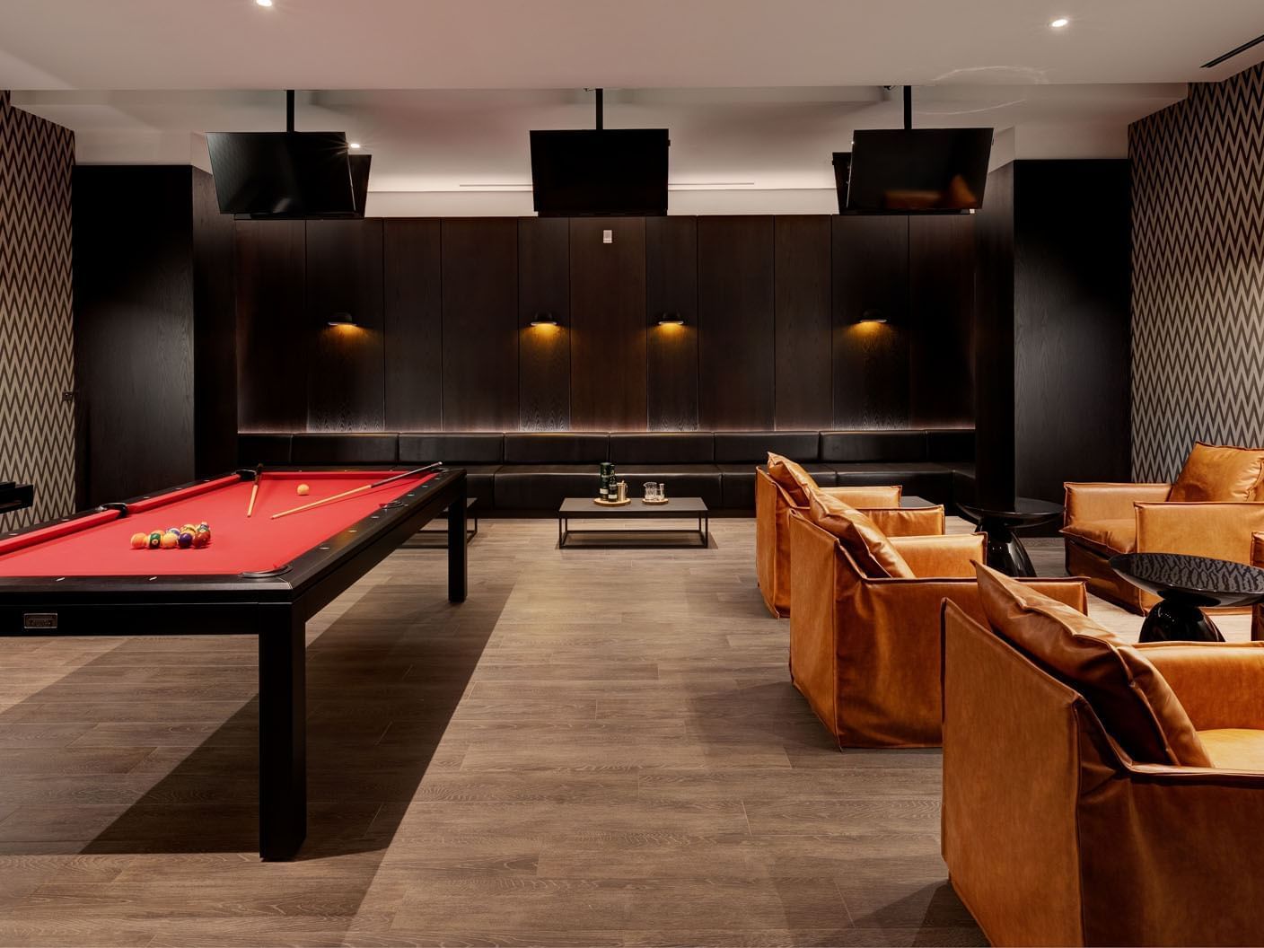 The Bow Tie lounge with a pool table, leather chairs, and ambient lighting at Hotel X Toronto