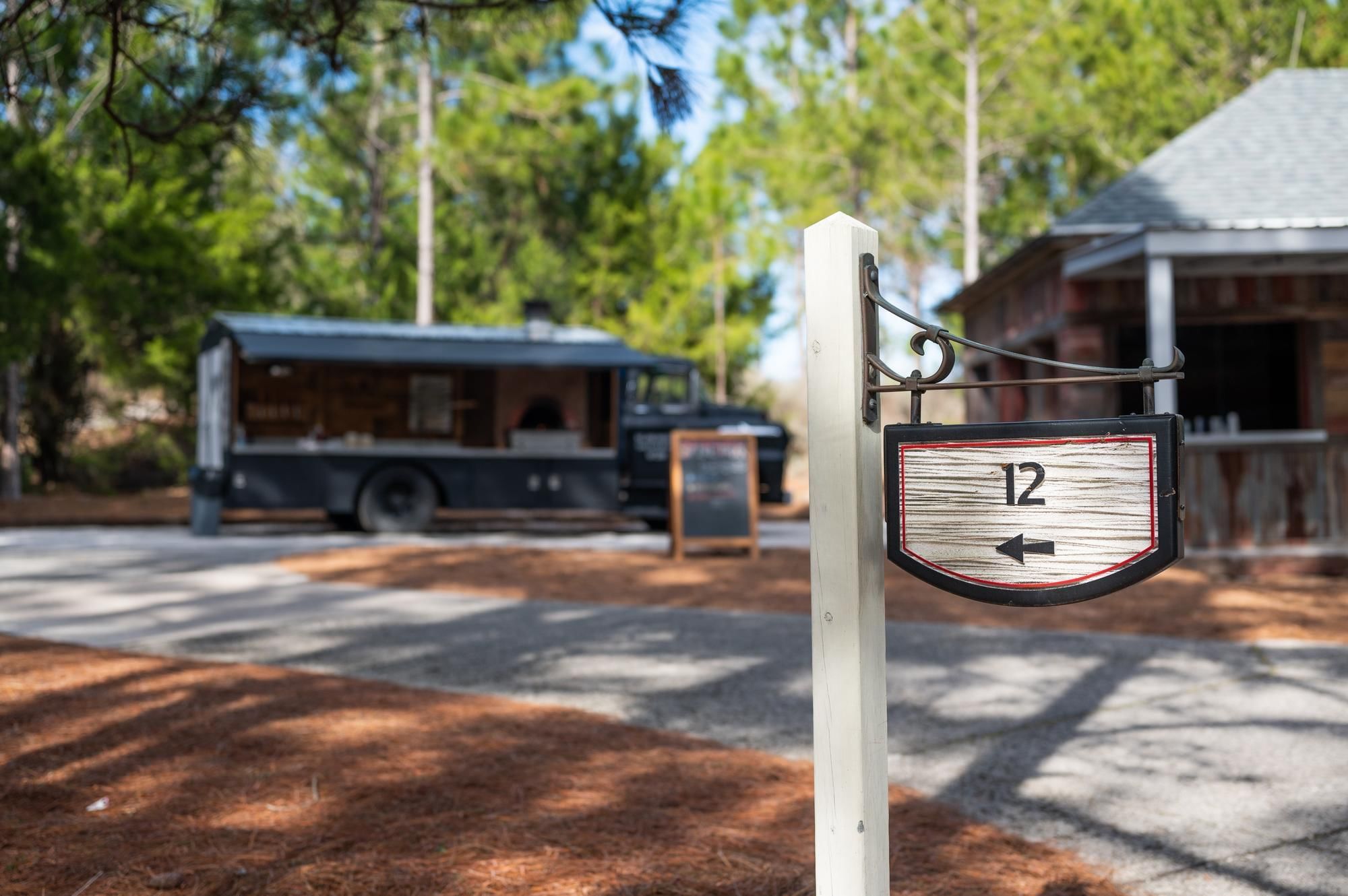 A post with a sign directing to the number 12 next to a food truck and building.