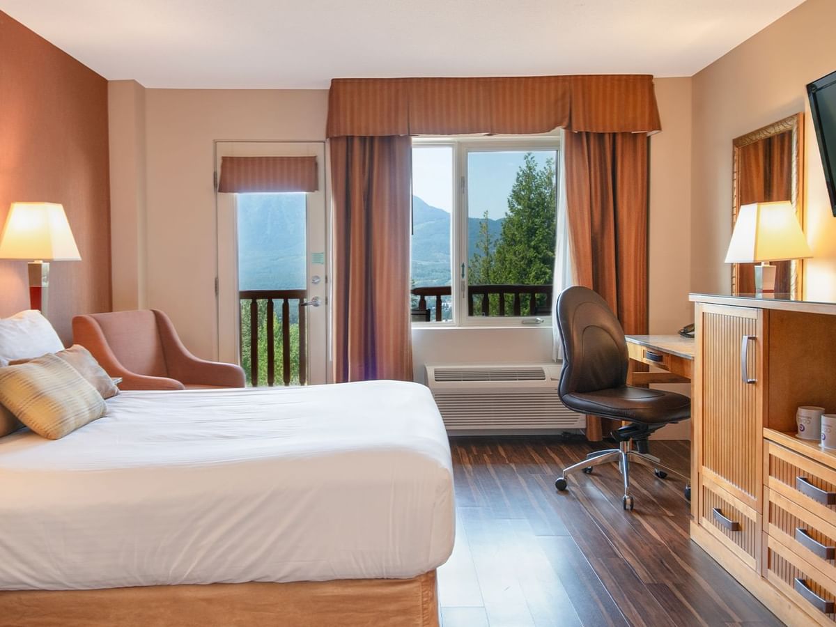 Hotel guest room with a queen bed, TV, work desk and a balcony