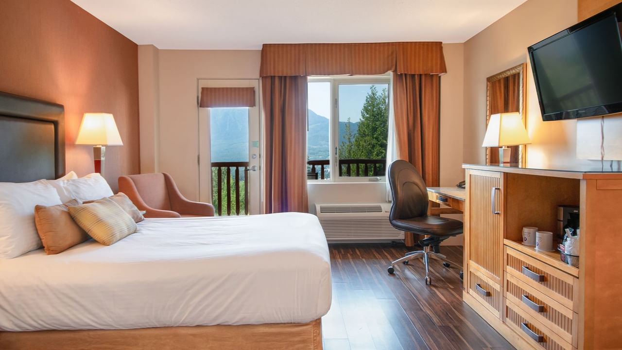 Hotel guest room with a queen bed, TV, work desk and a balcony
