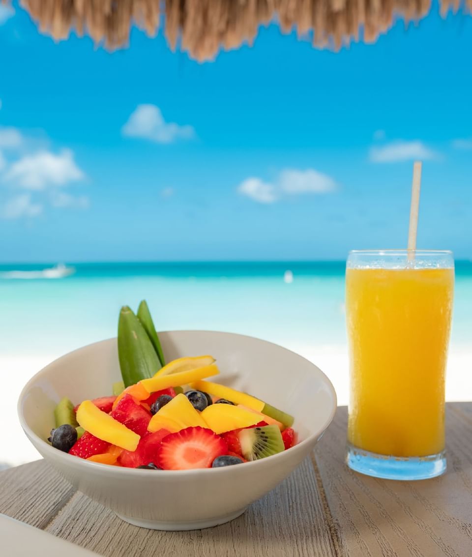 Fruit salad with fresh juice served on beachside dining table at Passions on the Beach