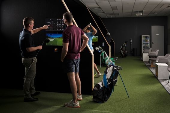 People in The Golf Bunker practicing golf at Alcyone Hotel Residences