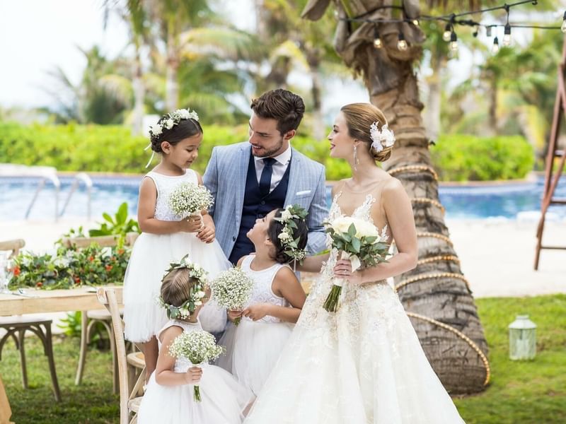 Portrait of groom, bride & flower girls by pool at FA Cozumel