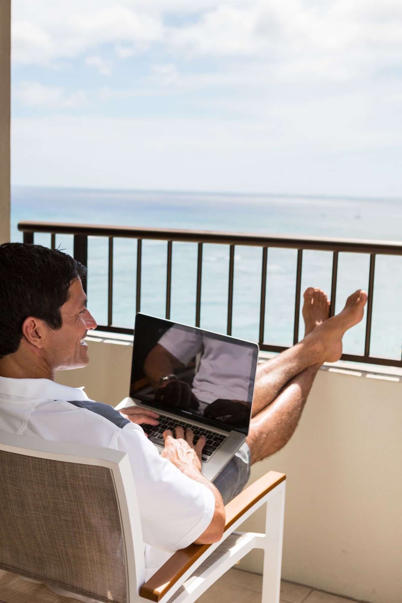 A person working with his laptop and overlooking the sea from Waikiki Resort Hotel