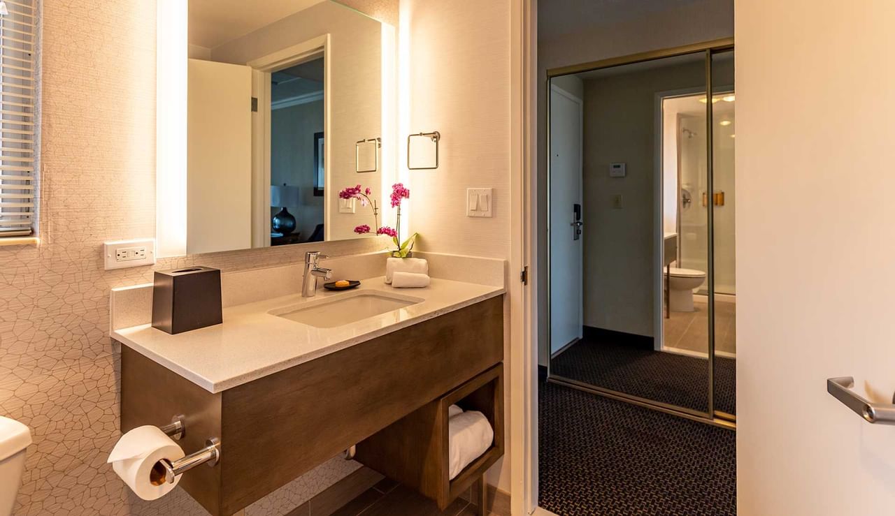 A bathroom with a vanity, mirror, toilet and shower