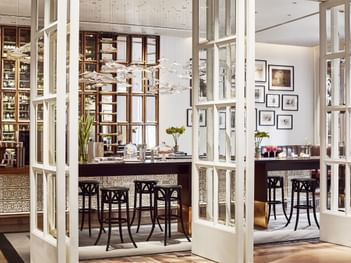 Opera entrance with glass doors revealing modern interior, bar, and plush seating at Park Hyatt Saigon
