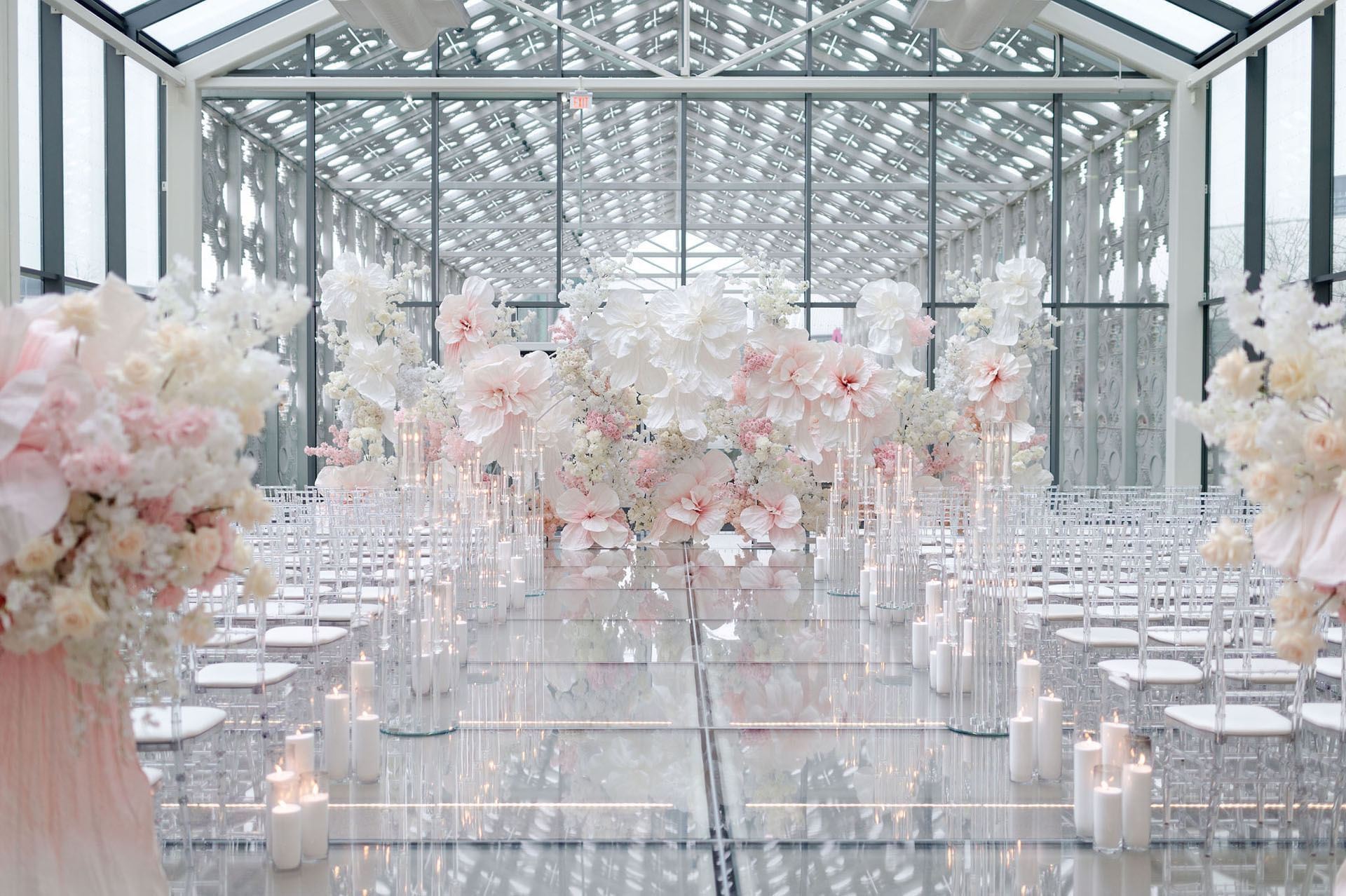 Elegant wedding aisle with white flowers, candles, and transparent chairs in New Fort Hall at Hotel X Toronto