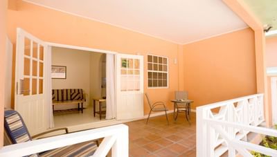 Spacious orange balcony with outdoor seating beside large white French doors open wide at Worthing Court Apartment