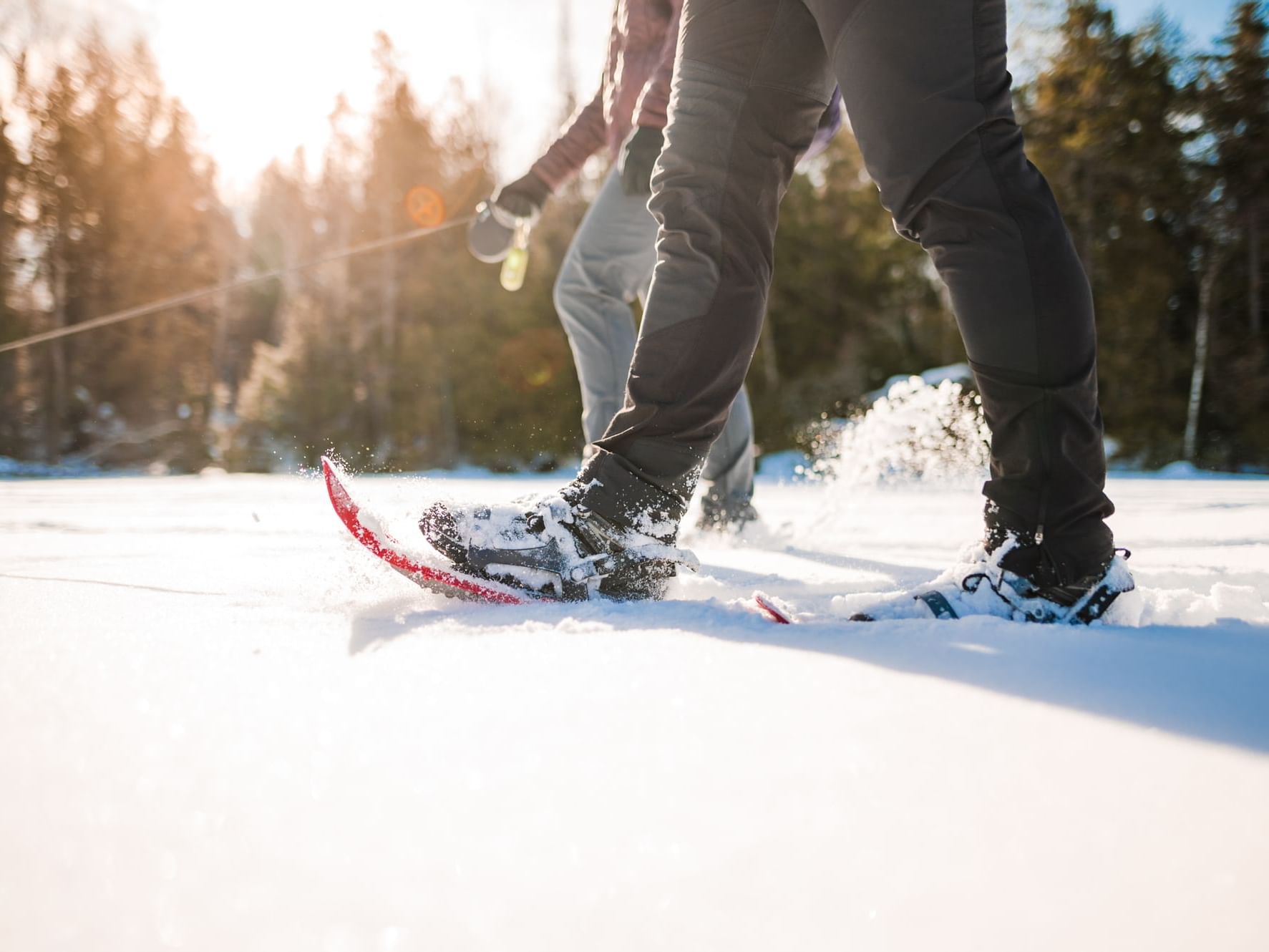 2 people walking on fresh snow with snowshoes near High Peaks Resort