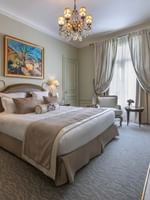Deluxe Suite Parisienne room with large bed and chandelier at Hôtel Westminster - Paris.