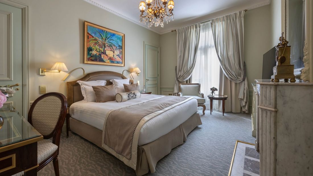 Chambre « Deluxe Suite Parisienne » avec grand lit et lustre à l'Hôtel Westminster - Paris.