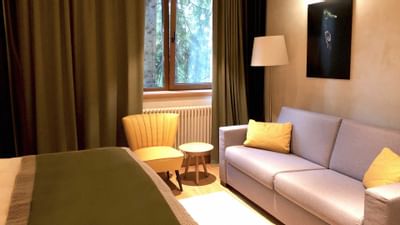 Bed & sofa with wall art in King Room at Ana Hotels