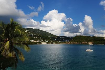 Sailboats floating on calm ocean waters under a cloudy blue sky near the Lindbergh Bay Hotel & Villas