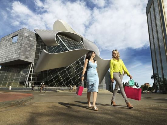 Two women walking with shopping bags in front of modern building