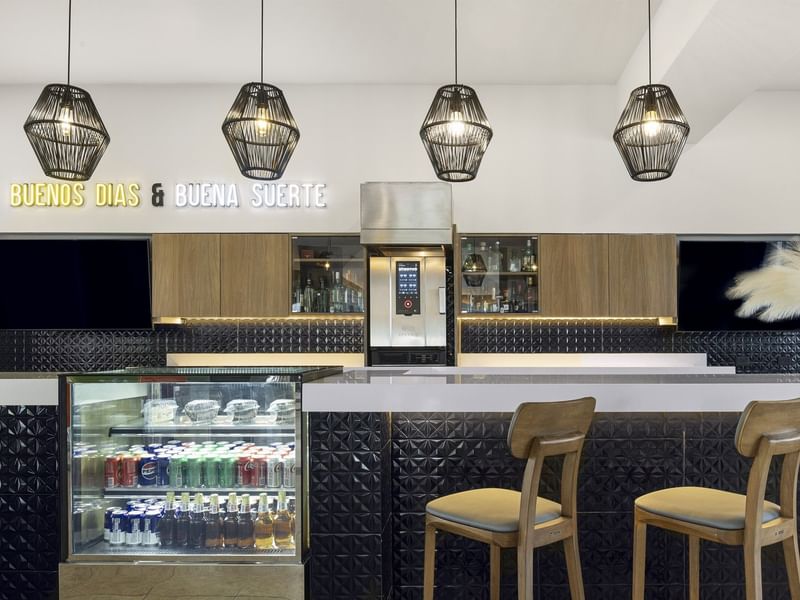 Stylish modern bar area at Fiesta Inn Express Nuevo Laredo featuring a neon sign reading, Buenos Días & Buena Suerte