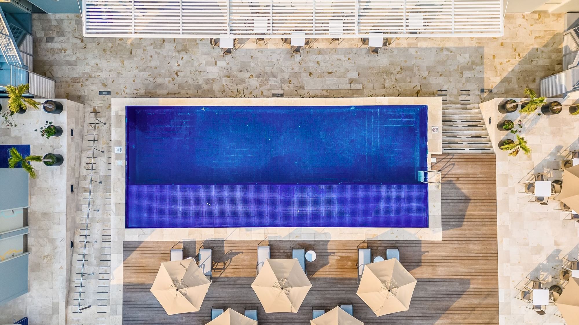 High-angle view of Outdoor pool area with sun loungers & patio umbrellas at One Acapulco Costera