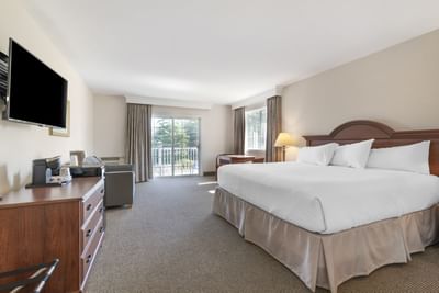 Bright One-bedroom Suites at Ogunquit Hotel and Suites with a large bed, wooden furniture, TV, and sunlit balcony access