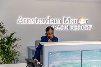 Reception desk with sleek counter, computer, and staff at Amsterdam Manor Beach Resort