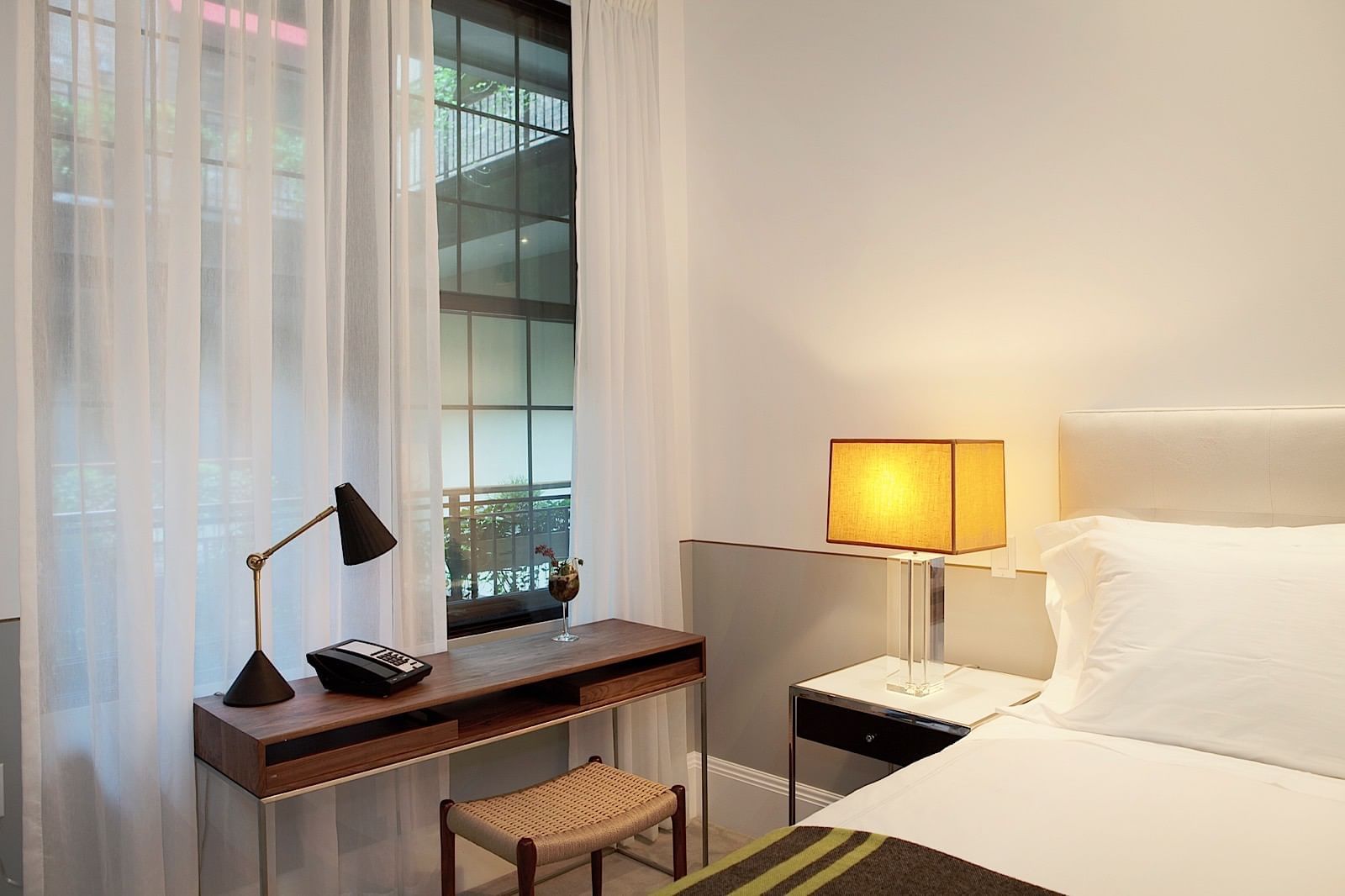 A hotel room with a bed, desk, and window