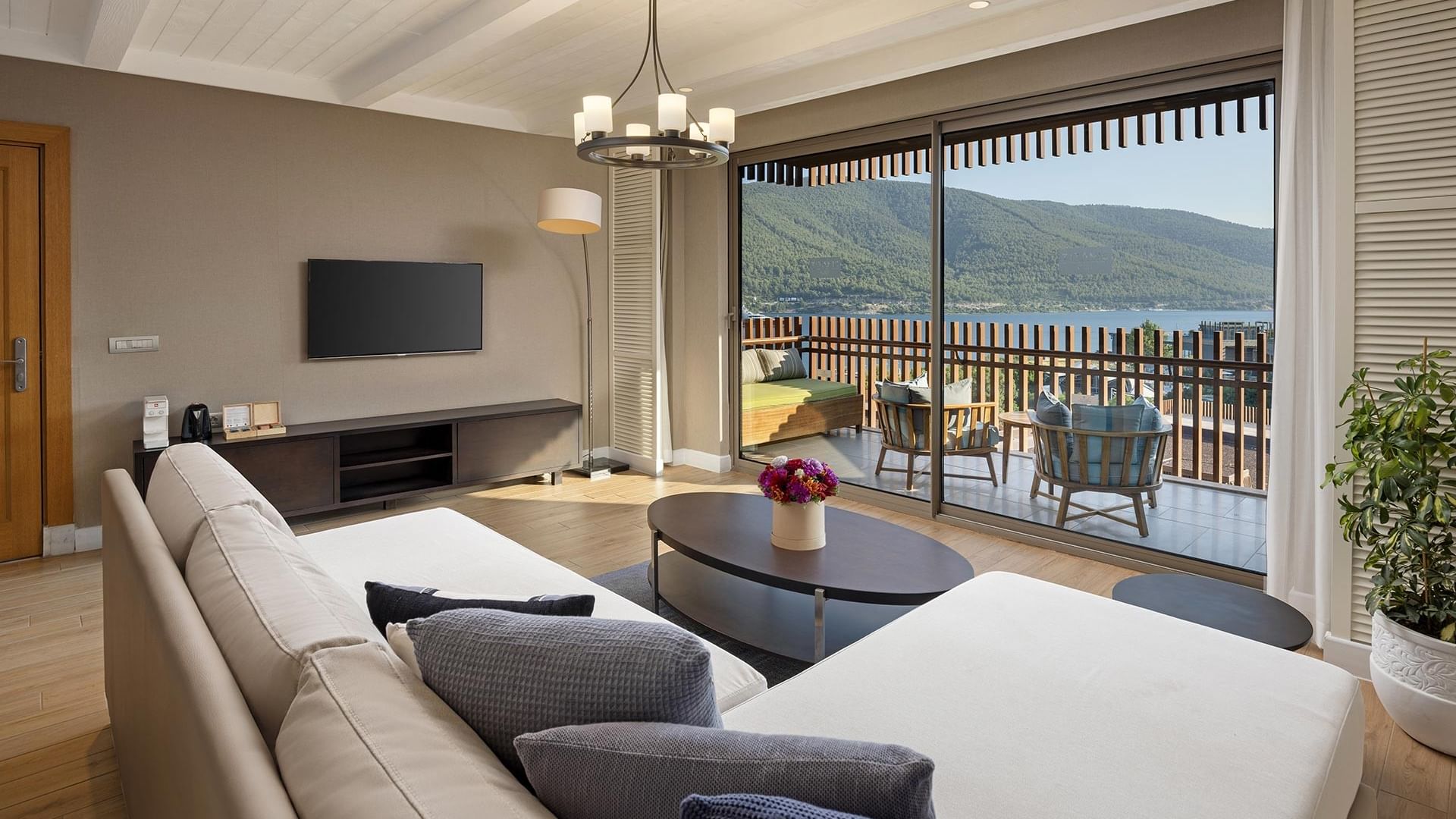 Гостиная зона семейного люкса в Titanic Luxury Collection Bodrum с балконом с видом, угловым диваном, журнальным столиком и телевизором.