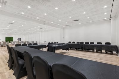 Spacious ballroom at The Riverwalk Plaza Hotel with long tables covered in black cloth and black chairs