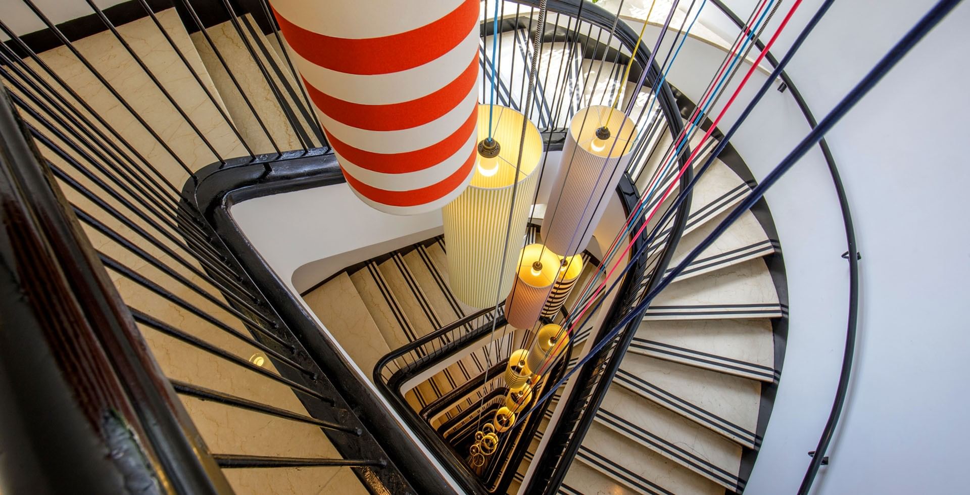 Design staircase at Tribune Hotel Rome with spiral architecture, artistic hanging lights, and modern geometric details creating a stylish interior feature.