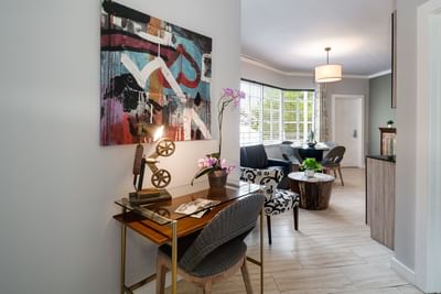 Entrance hallway with a desk and orchid leading into the living and dining area of an apartment at Tradewinds Apartment Hotel