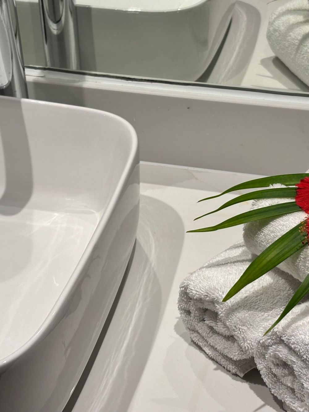 A bathroom sink with a red flower on towels in an Ocean View Two Double Room at Warwick Fiji, Korolevu.