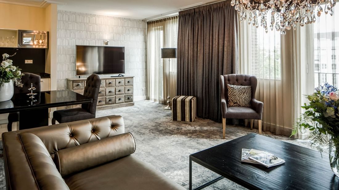 TV lobby area with couches and dining table in Imperial Suite at Luxury Suites Amsterdam