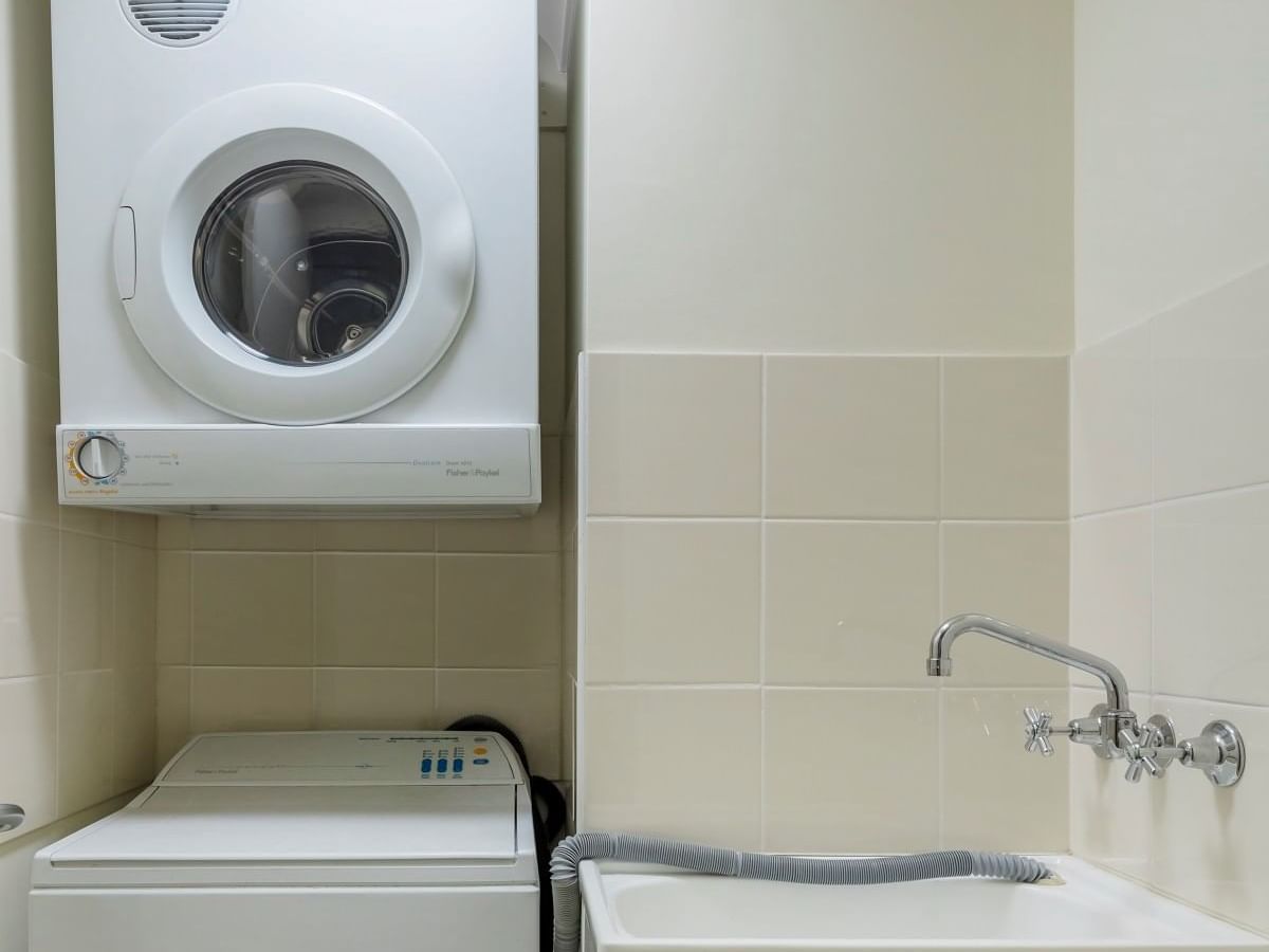 A compact laundry room with a washer and dryer at Nesuto Canberra Apartment Hotel