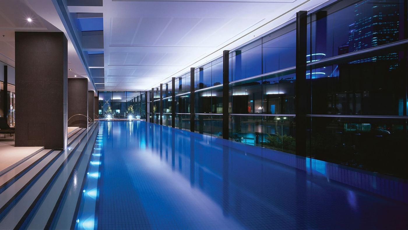 Indoor pool area with a city view at night in Crown Promenade Melbourne